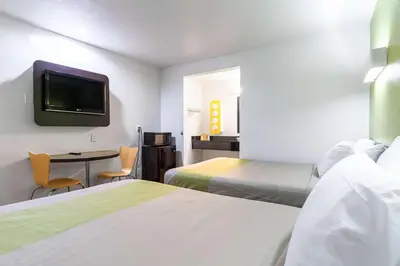 a room with two beds and a table with a tv at Motel 6 Riverside, CA - UCR East in Riverside