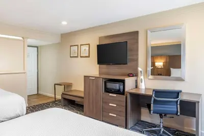 a hotel room with a desk with a television and a bed at Best Western Plus Hill House in Bakersfield