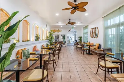 a restaurant with tables and chairs and a ceiling fan at Best Western Plus Hill House in Bakersfield