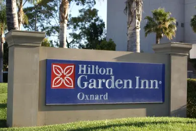 a sign for the hilinson garden inn in front of palm trees at Hilton Garden Inn Oxnard/Camarillo in Oxnard