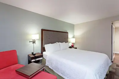a hotel room with a bed and a red chair at Hampton Inn Los Angeles/Arcadia in Arcadia