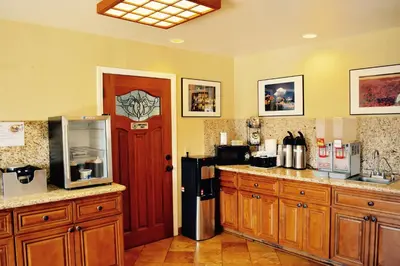 a kitchen with wooden cabinets and a refrigerator and a door at Days Inn by Wyndham Anaheim Near the Park in Anaheim