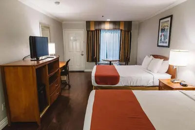 a hotel room with two beds and a flat screen tv at Best Western Palm Garden Inn in Westminster