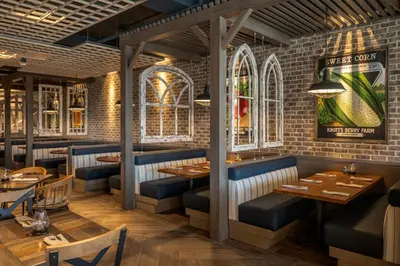 a restaurant with tables and chairs and a brick wall at Knott's Hotel in Buena Park