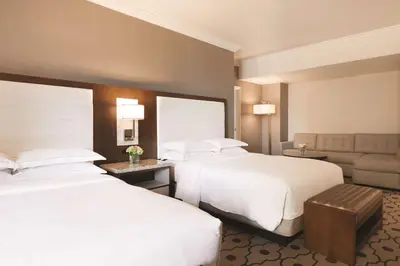 a hotel room with two beds and a couch at Hilton Los Angeles/San Gabriel in San Gabriel