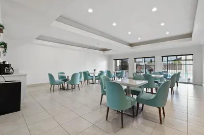 a dining room with green chairs and tables and windows at Brookhurst Plaza Inn in Anaheim