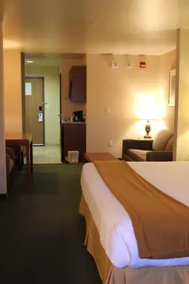 a hotel room with a bed and a living room at Holiday Inn Express Tehachapi by IHG in Tehachapi