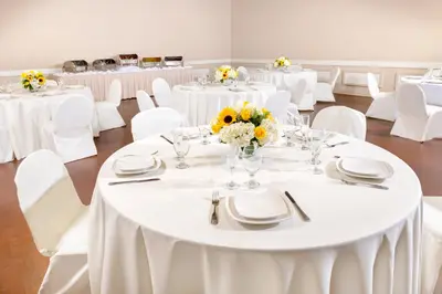a room filled with white tables and white chairs at Clocktower Inn Ventura in Ventura