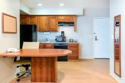 a kitchen with wooden cabinets and a wooden table at Candlewood Suites LAX Hawthorne by IHG in Hawthorne