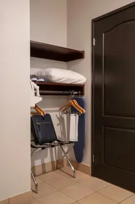 a room with a bed and a chair next to a door at Ayres Hotel Chino Hills Ontario in Chino Hills