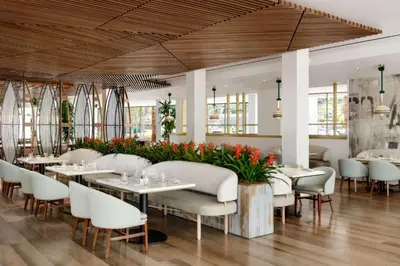 a restaurant with white tables and chairs and flowers at Hilton Los Angeles-Culver City, CA in Los Angeles