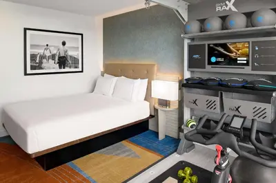 a small bedroom with a bed and a treadmill at Hilton Los Angeles-Culver City, CA in Los Angeles