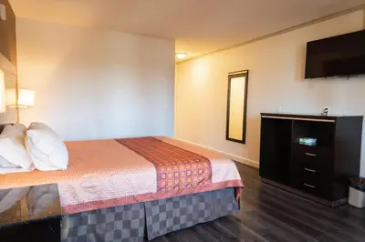 a hotel room with a bed and a flat screen tv at Maywood Inn in Maywood