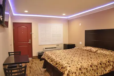 a bedroom with a bed and a table and a red door at Sun Light Motel in Downey
