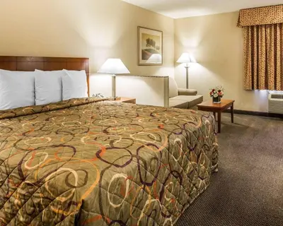 a hotel room with a large bed and a couch at California Inn and Suites Bakersfield in Bakersfield