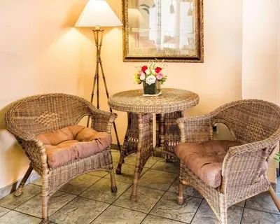 a table with two chairs and a table with flowers on it at California Inn and Suites Bakersfield in Bakersfield