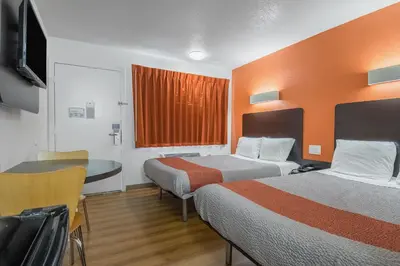 a hotel room with two beds and a table and a desk at Motel 6 Bakersfield in Bakersfield