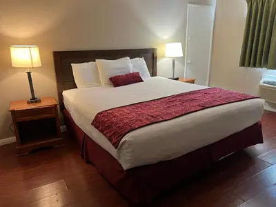 a large bed in a hotel room with two lamps at Hometown Inn North Hills in North Hills