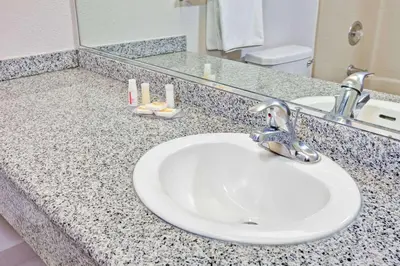 a bathroom counter with a sink and a mirror at Days Inn & Suites by Wyndham Fullerton in Fullerton