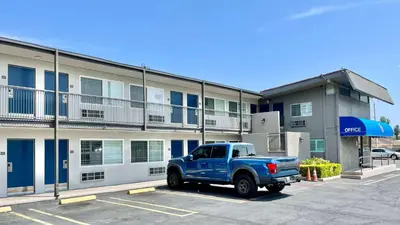 a blue truck parked in a parking lot in front of a building at Motel 6 Pico Rivera - Los Angeles, CA in Pico Rivera