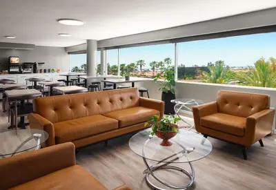 a waiting room with couches and tables and windows at Sheraton Ontario Airport Hotel in Ontario
