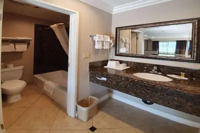 a bathroom with a sink and a toilet and a mirror at Super 8 by Wyndham Cypress Buena Park Area in Cypress