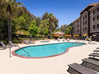 a pool at a hotel with chairs and trees at La Quinta by Wyndham Santa Clarita - Valencia in Stevenson Ranch
