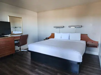 a bedroom with a bed and a desk and a television at Motel 6 Barstow, CA - Lenwood Road in Barstow