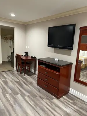 a hotel room with a desk and a flat screen tv at Travelodge by Wyndham Brea in Brea