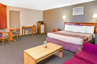 a hotel room with a bed and a table at Super 8 by Wyndham Upland Ontario CA in Upland