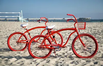 a red bike is parked on the beach at The Kinney - Venice Beach in Los Angeles