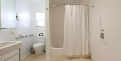 a white bathroom with a shower curtain and a toilet at Su Casa at Venice Beach in Los Angeles