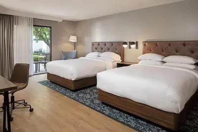 a hotel room with two beds and a table and a desk at Four Points by Sheraton Bakersfield in Bakersfield
