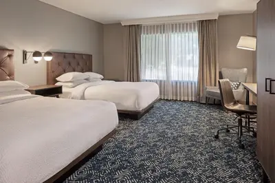 a hotel room with two beds and a desk at Four Points by Sheraton Bakersfield in Bakersfield