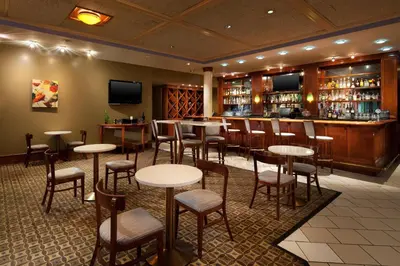a restaurant with tables and chairs and a bar at Four Points by Sheraton Bakersfield in Bakersfield