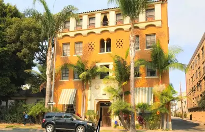 a black suv parked in front of a yellow building at Casa Bonita Apartments in Long Beach