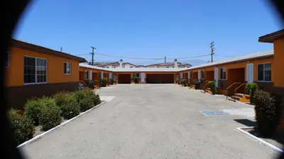 an empty parking lot in front of a row of buildings at Aristocrat Motel in Baldwin Park