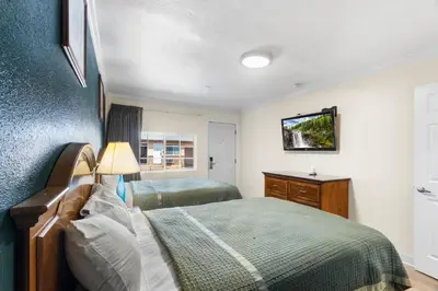 a bedroom with a bed and a tv on a wall at Aristocrat Motel in Baldwin Park