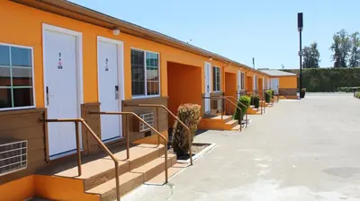 an orange building with a row of doors and stairs at Aristocrat Motel in Baldwin Park