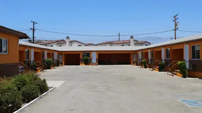 a row of orange buildings in a parking lot at Aristocrat Motel in Baldwin Park