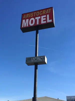 a sign for an apartment motel on a pole at Aristocrat Motel in Baldwin Park