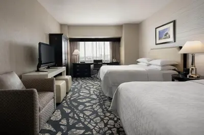 a hotel room with two beds and a flat screen tv at Sheraton Garden Grove-Anaheim South in Anaheim