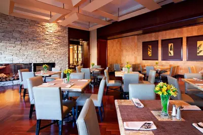 a restaurant with tables and chairs and a fireplace at Sheraton Garden Grove-Anaheim South in Anaheim