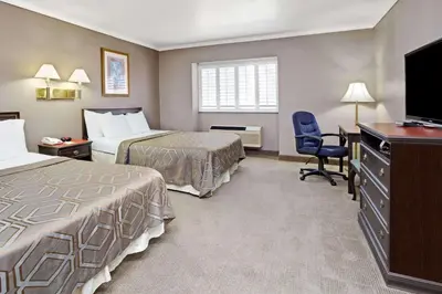 a hotel room with two beds and a flat screen tv at Days Inn by Wyndham West Covina in West Covina
