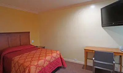a hotel room with a bed and a desk and a television at Rosa Bell Motel - Los Angeles in Los Angeles