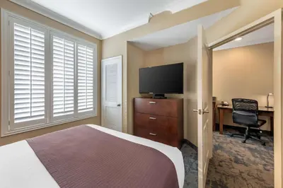 a bedroom with a bed and a desk and a television at Best Western PLUS Avita Suites in Torrance