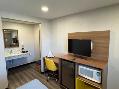 a hotel room with a desk with a television and a sink at Days Inn by Wyndham Barstow in Barstow