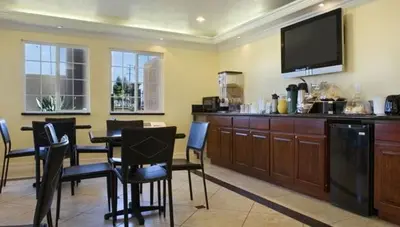 a dining room with a table and a flat screen tv at Orange Show Inn in San Bernardino