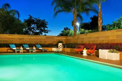 a swimming pool with chairs chairs and a fence at Aloft Ontario-Rancho Cucamonga in Rancho Cucamonga