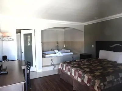 a hotel room with a bed and a desk and a desk at West Coast Inn Santa Ana in Santa Ana